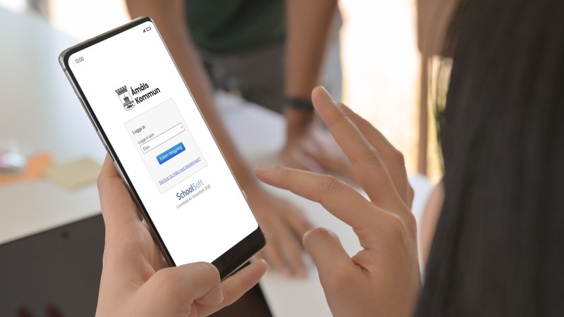 Person som använder deras telefon för att logga in på SchoolSoft.